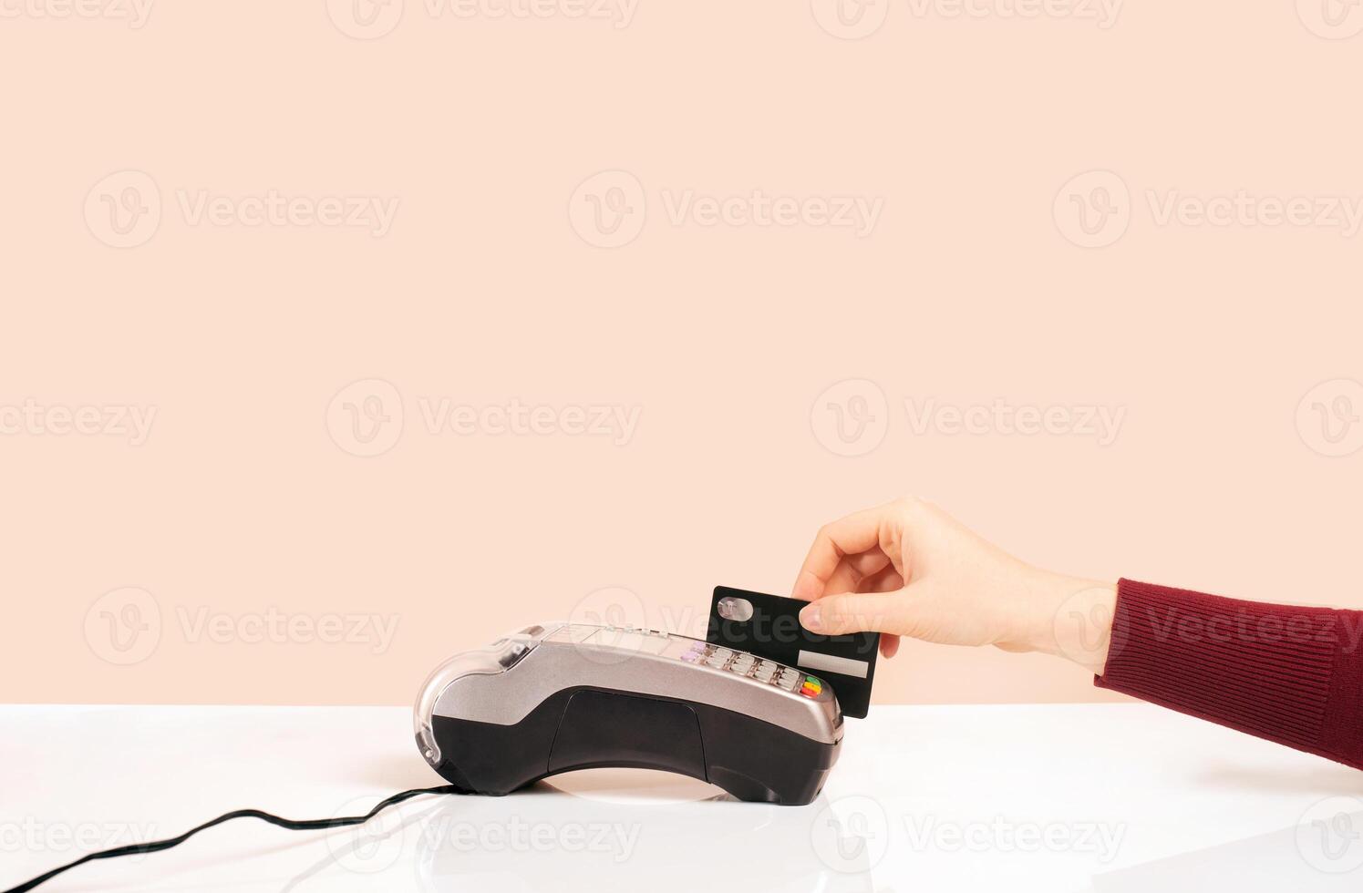 Customer hand near bar counter make payment use black credit card, hands device view, cashless method pay bills in on pink or coral background. minimalism photo