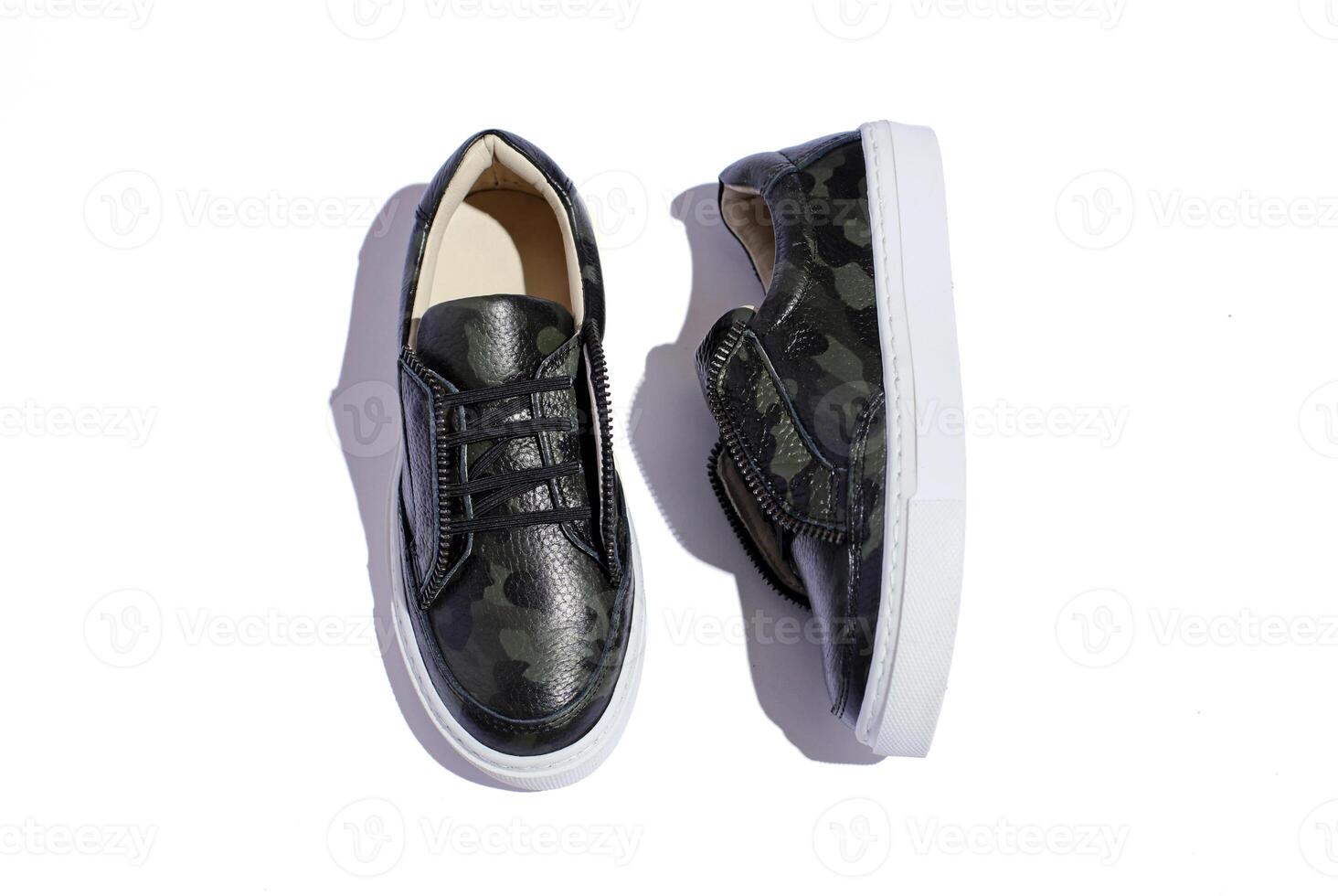green camouflage sneakers on white background top view with hard shadows. photo