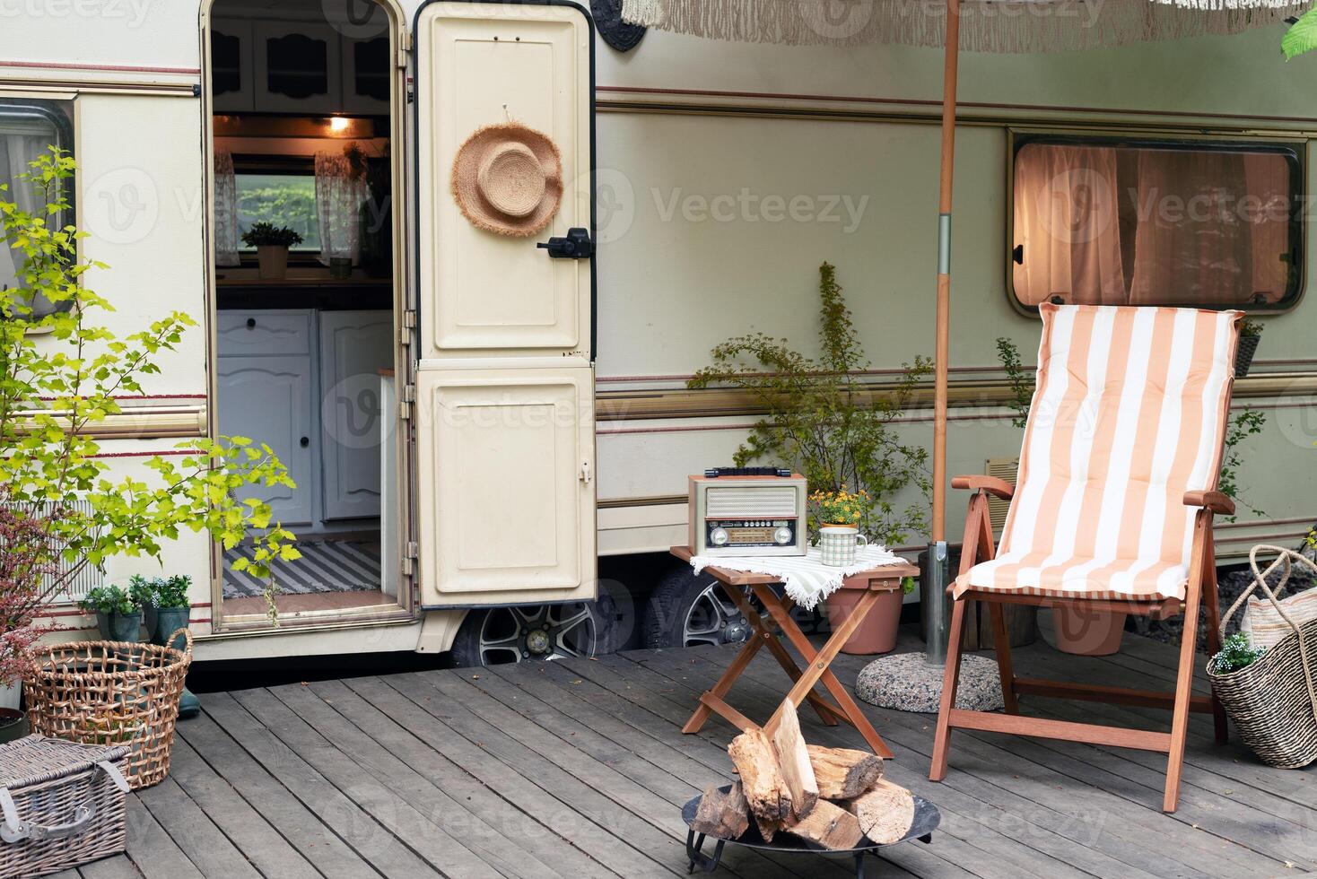 Terrace mobile home in spring, mobile home, green leaves, sun lounger with blanket, flowerpot, table and bonfire photo