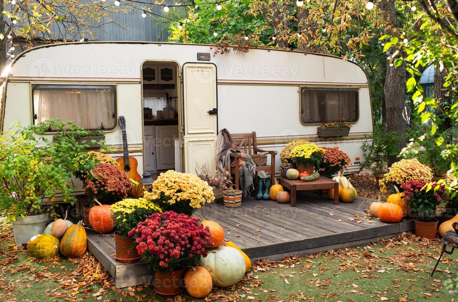 Mobile home van with terrace in autumn, mobile home, orange fallen leaves. autumn decor, pumpkins photo