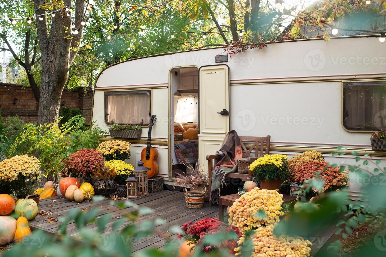 Mobile home van with terrace at sunset in autumn, mobile home, orange fallen leaves. autumn decor, pumpkins photo