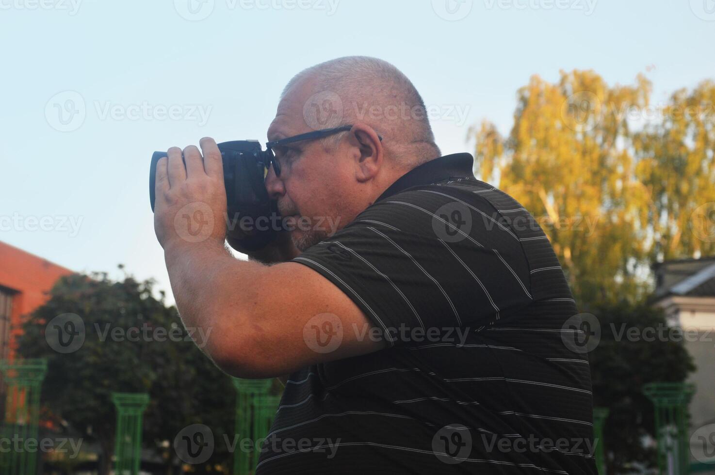 Caucasian man photographer with a modern camera takes photo pictures on a city street.