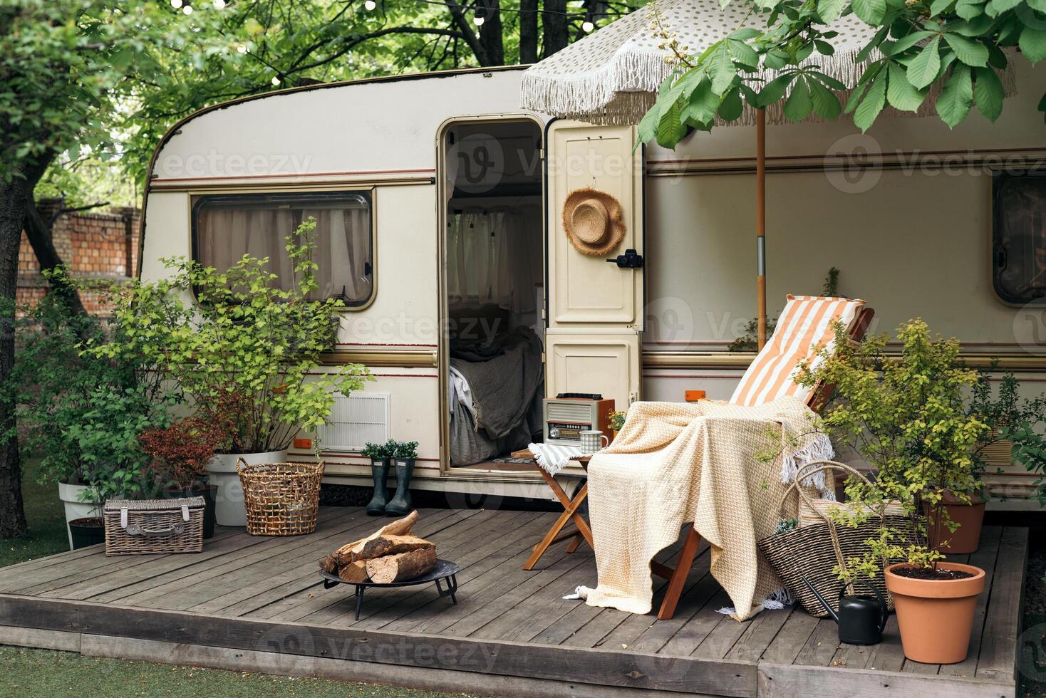 Terrace mobile home in spring, mobile home, green leaves, sun lounger with blanket, flowerpot, table and bonfire photo