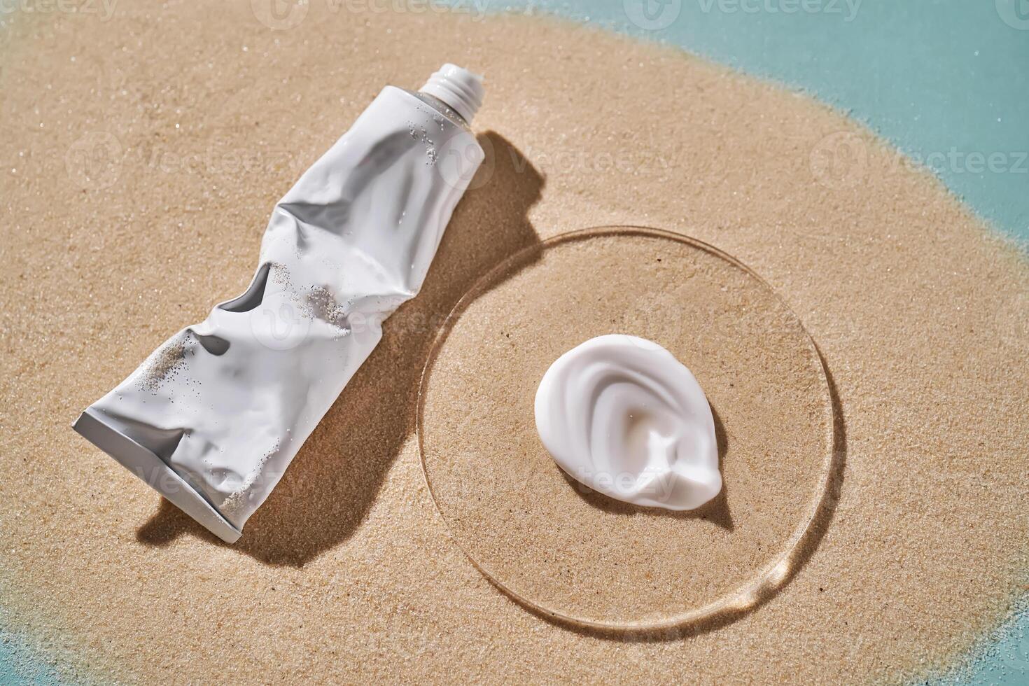 A tube of moisturizing sunscreen and a smear on a sandy background. photo