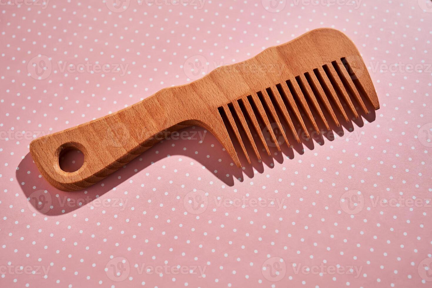 Wooden comb on a pink polka dot background. photo