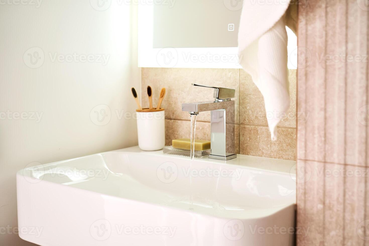 Bathroom sink with toothbrushes and running water. photo