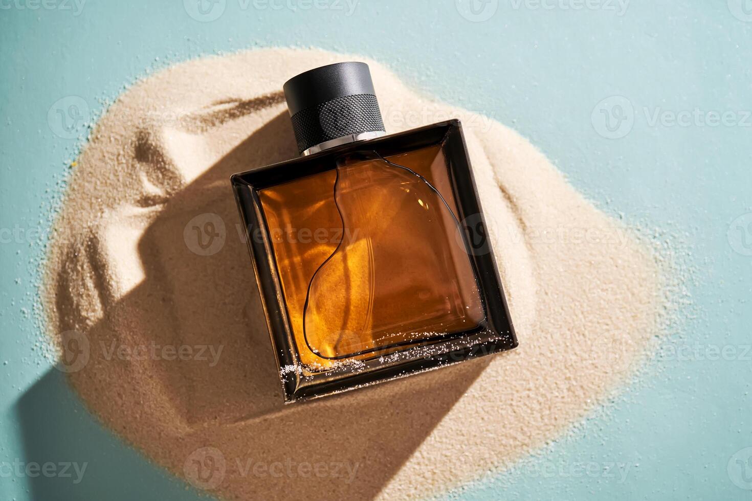 A bottle of perfume on a background of sand. photo