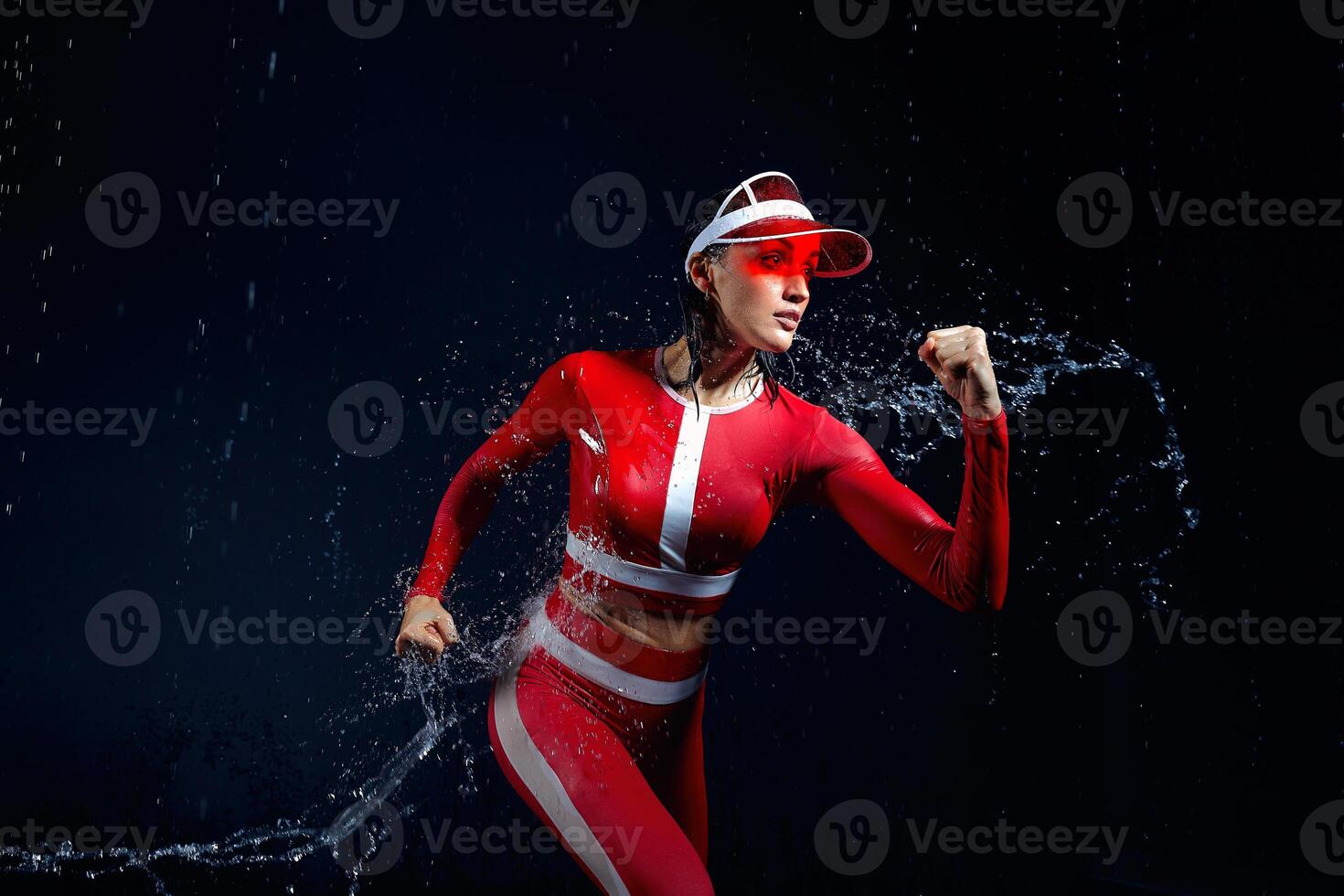 Beautiful young girl in sportswear runing in aqua studio. Drops of water spread about her fitness body. The perfect figure on the background of water splashes. Bad weather for sport photo