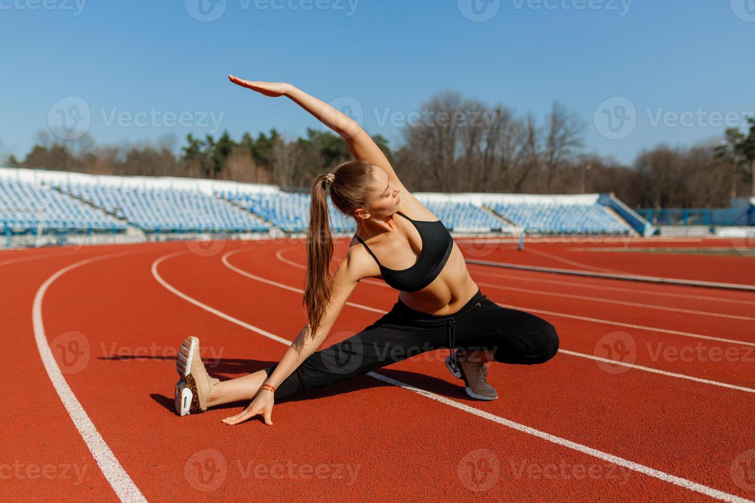 joven aptitud mujer corredor calentar arriba antes de corriendo en pista. Mañana ejercicios a verano foto