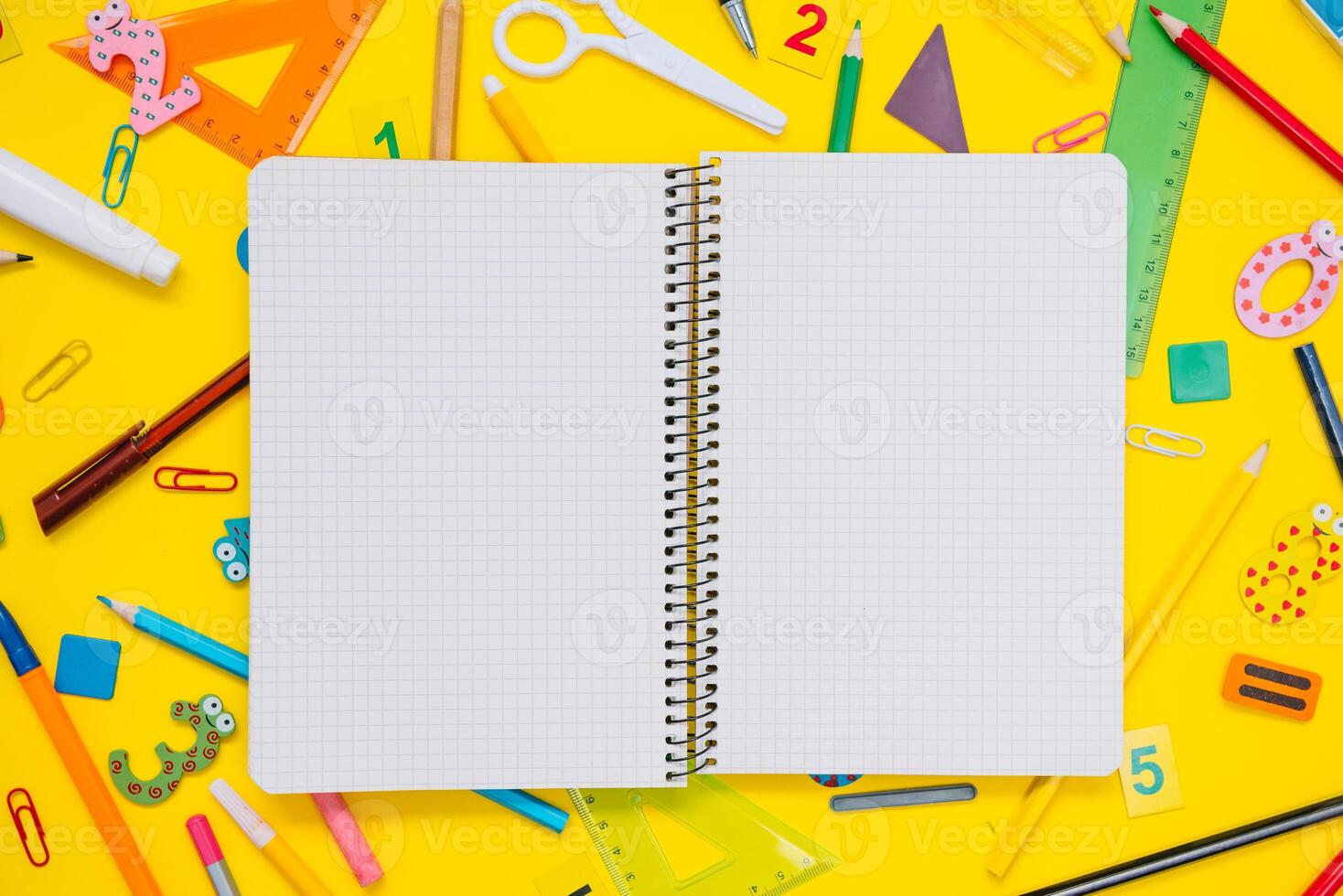 School notebook and stationery over yellow desk. Back to school abstract background. School equipment. Variety of school supplies. Flat lay photo