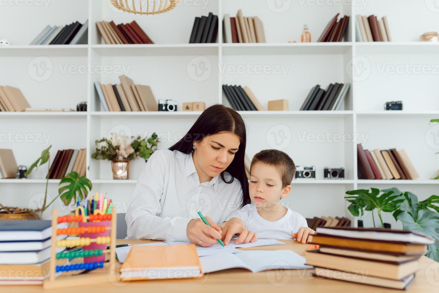 Portrait of smart tutor with pencil correcting mistakes in pupils notebook photo