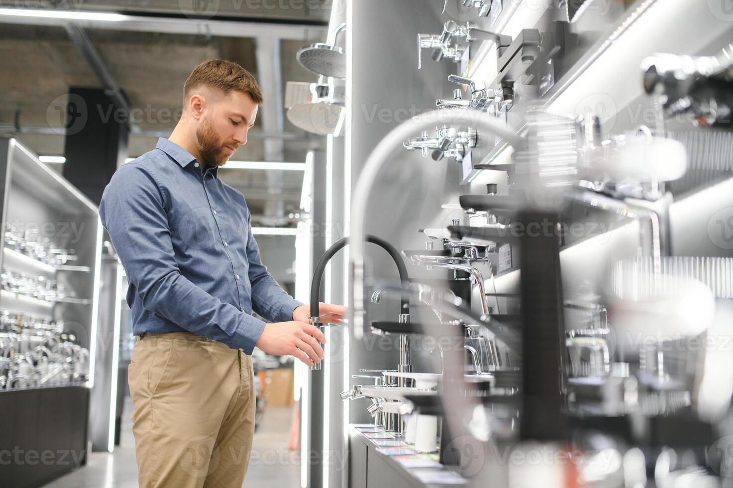 A large selection of water faucets. Man chooses a products in a sanitary ware store photo