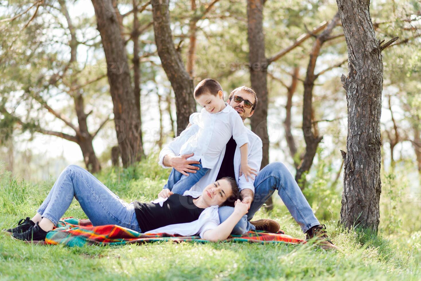 happy young family spending time outdoor on a summer day have fun at beautiful park in nature while sitting on the green grass. Happy family. photo