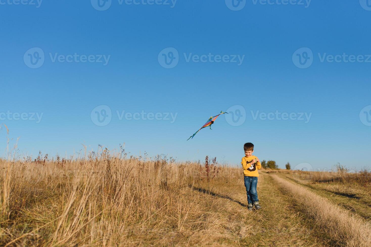 Little boy with kite flying over his head photo