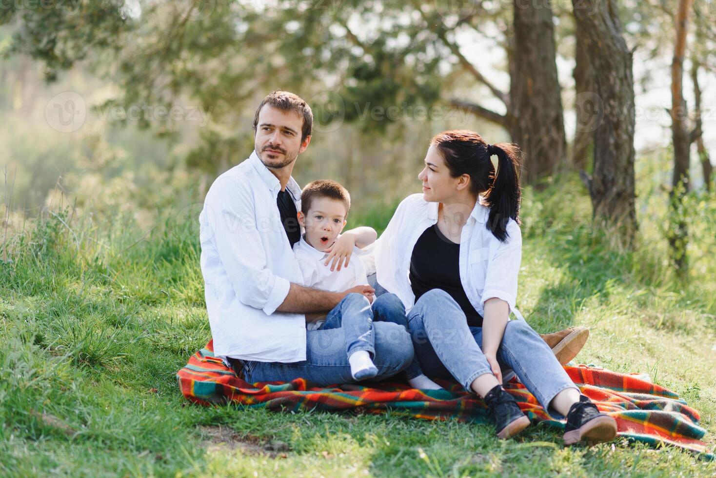 happy young family spending time outdoor on a summer day have fun at beautiful park in nature while sitting on the green grass. Happy family. photo