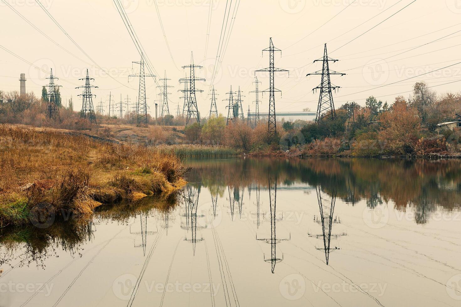 Coal power station in beautiful area full of trees and lake, mirror reflection of energetic pole and power station with chimneys, synergy of industry and nature photo