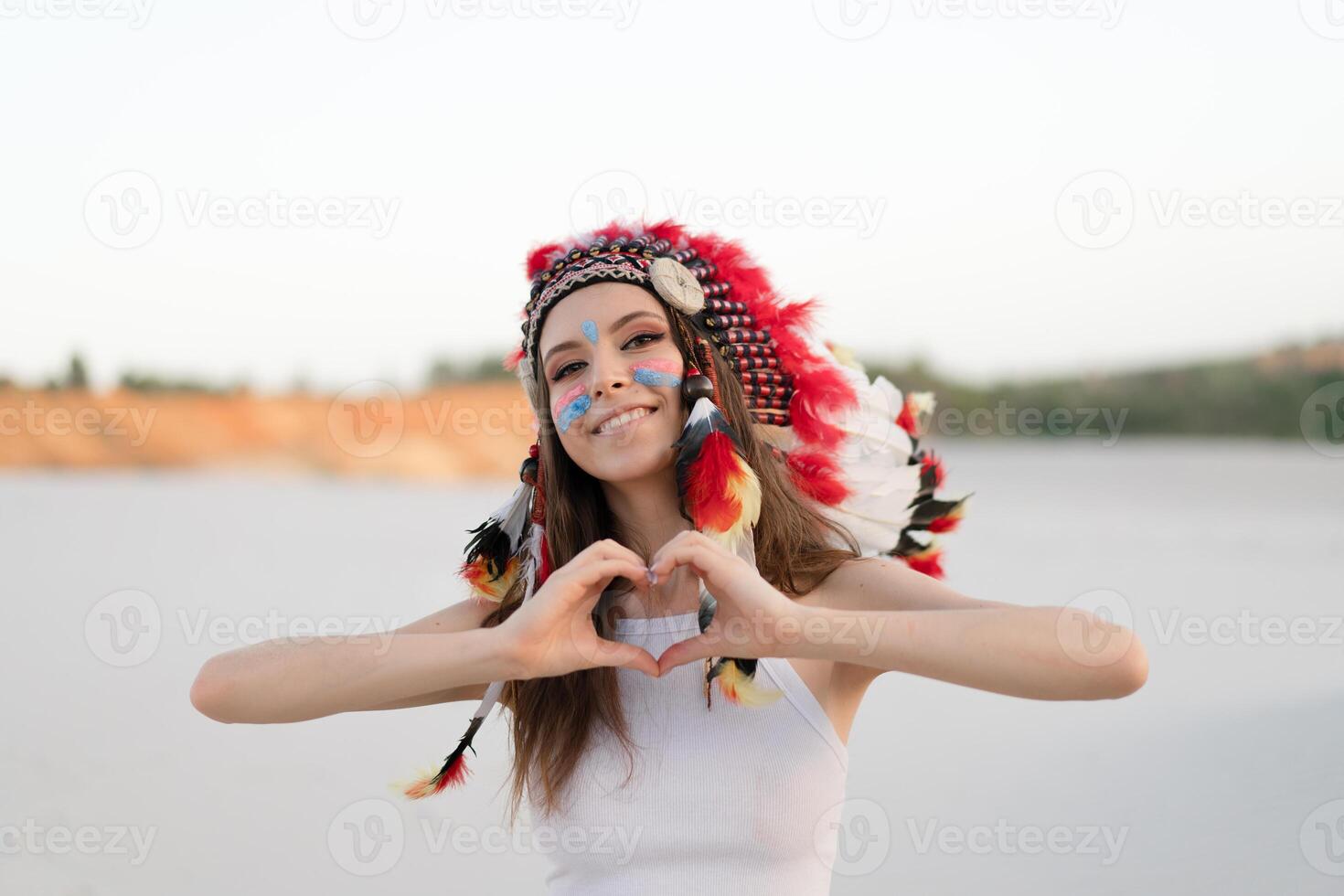 A beautiful young Caucasian girl in a white top on her head is wearing an Indian hat. Roach is in the desert. Happy holiday mood. photo