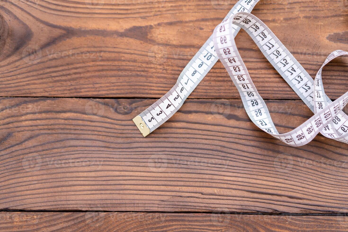 White measuring tape of a tailor lies in corner on dark wooden background. photo