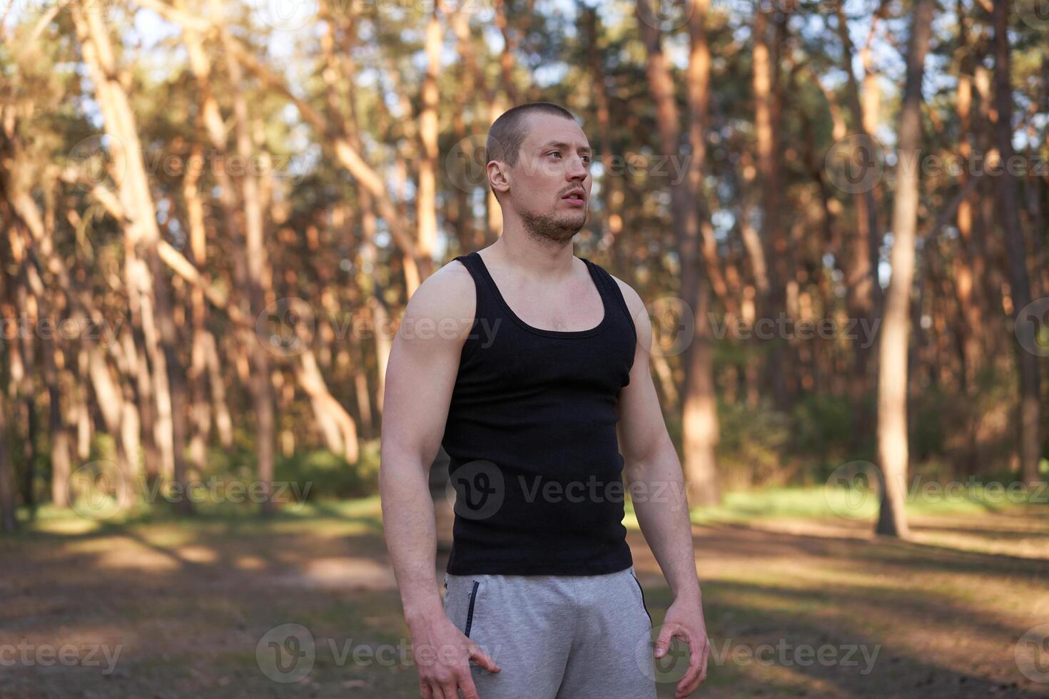 atlético hombre en pie al aire libre gimnasio ejercicio. hermoso caucásico chico cruzar formación naturaleza público gimnasia. foto