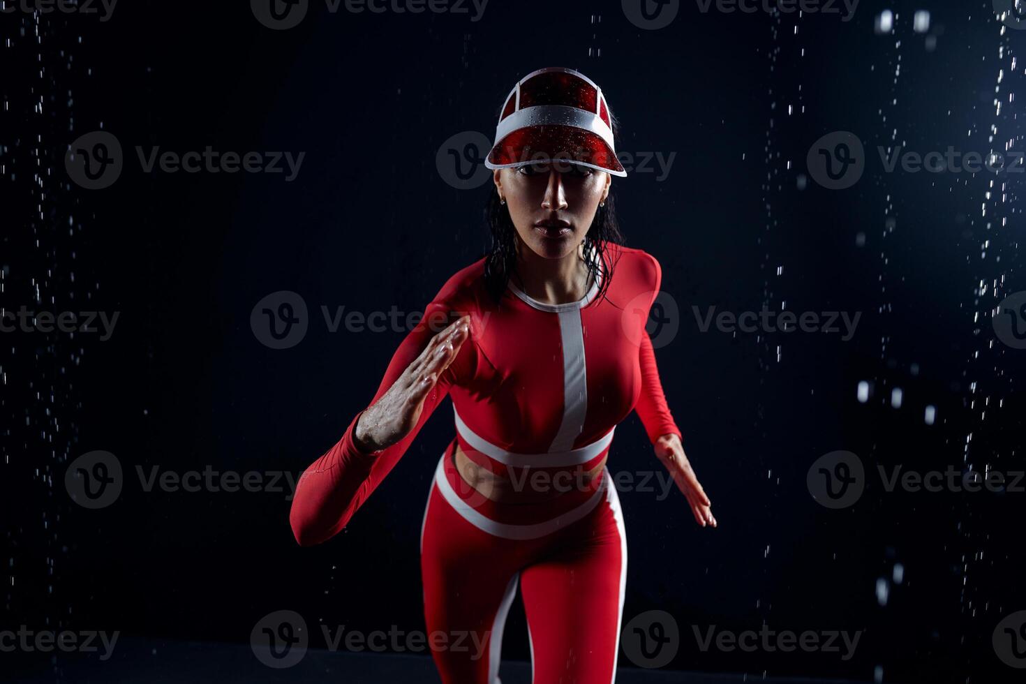 hermosa joven niña en ropa de deporte corriendo en agua estudio. gotas de agua untado acerca de su aptitud cuerpo. el Perfecto figura en el antecedentes de agua salpicaduras malo clima para deporte foto