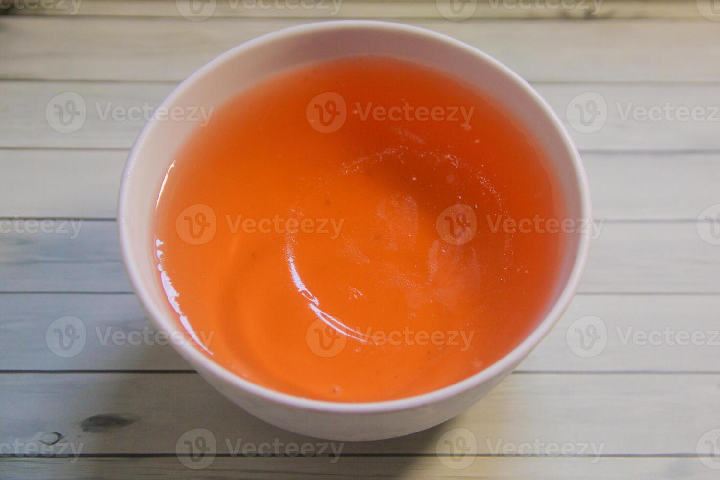 Orange jelly in a white bowl and isolated on a textured background photo