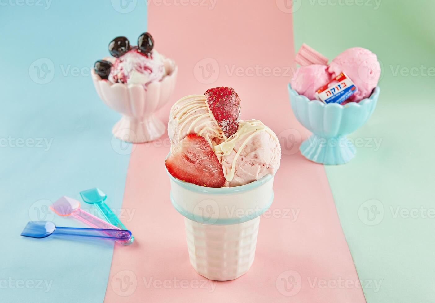 Three ice cream flavors in white and pink cups with spoons on a blue, pink, and green background. photo