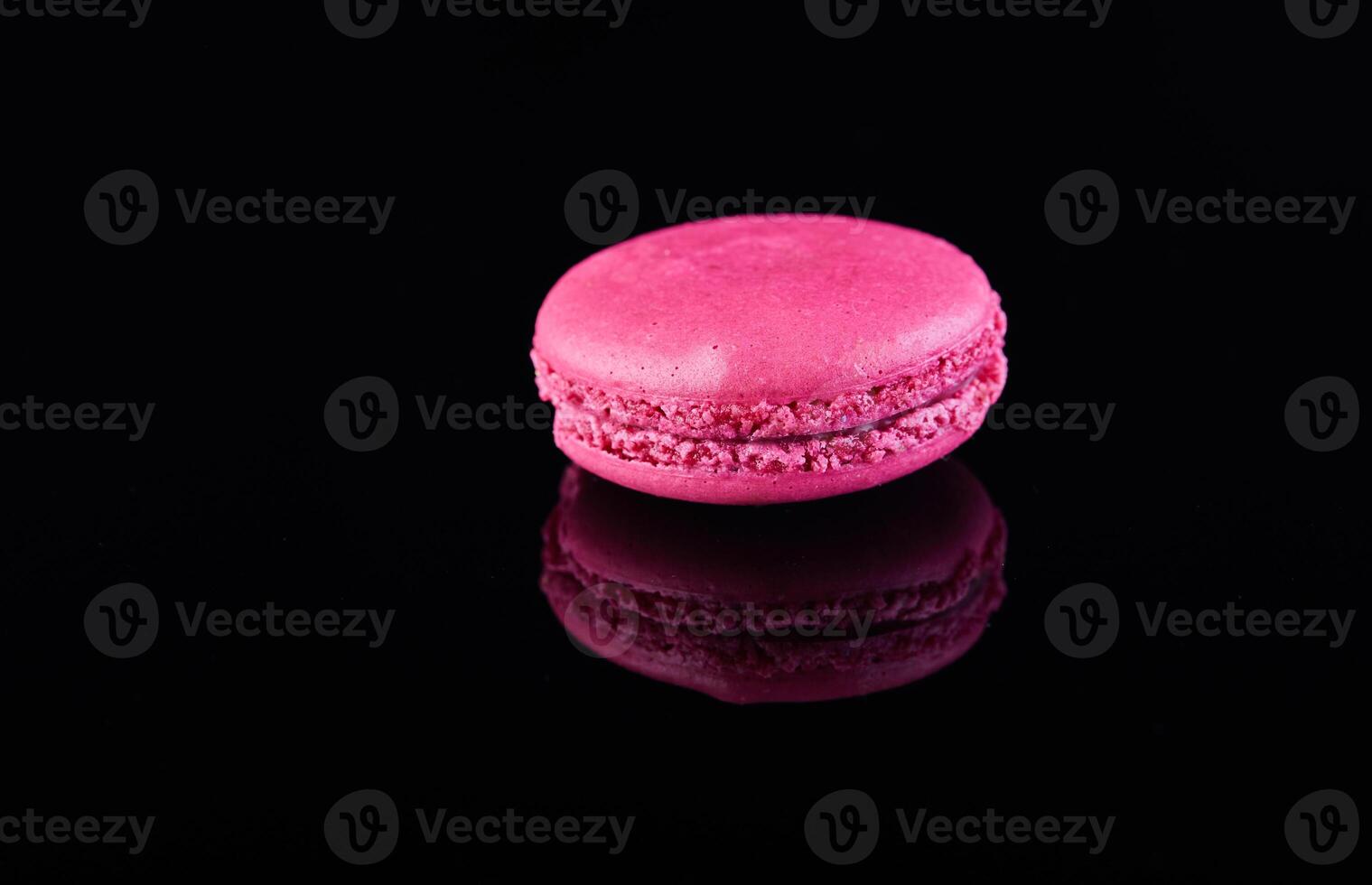 Assorted colorful macarons folded and arranged on a black surface with reflection photo