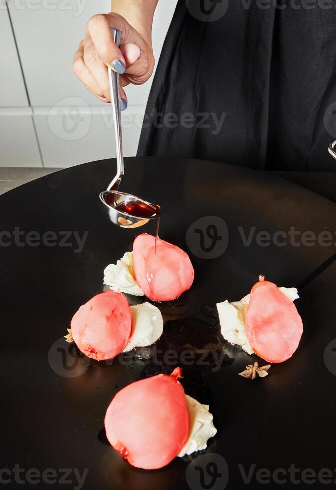 Artfully arranged poached pears with luscious cream cheese and drizzled syrup on elegant black plate photo