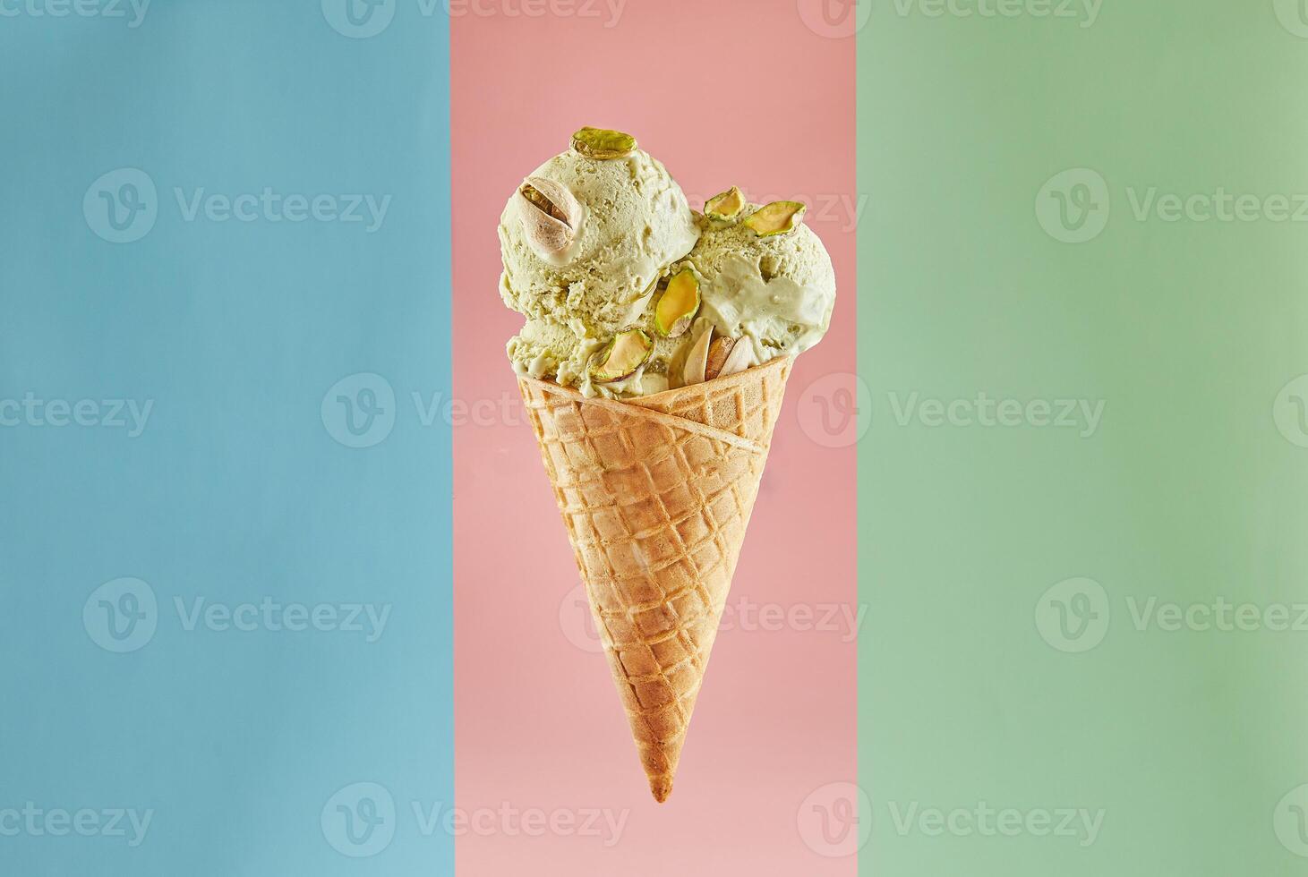 Single scoop of pistachio ice cream in a waffle cone isolated on three pastel color background photo