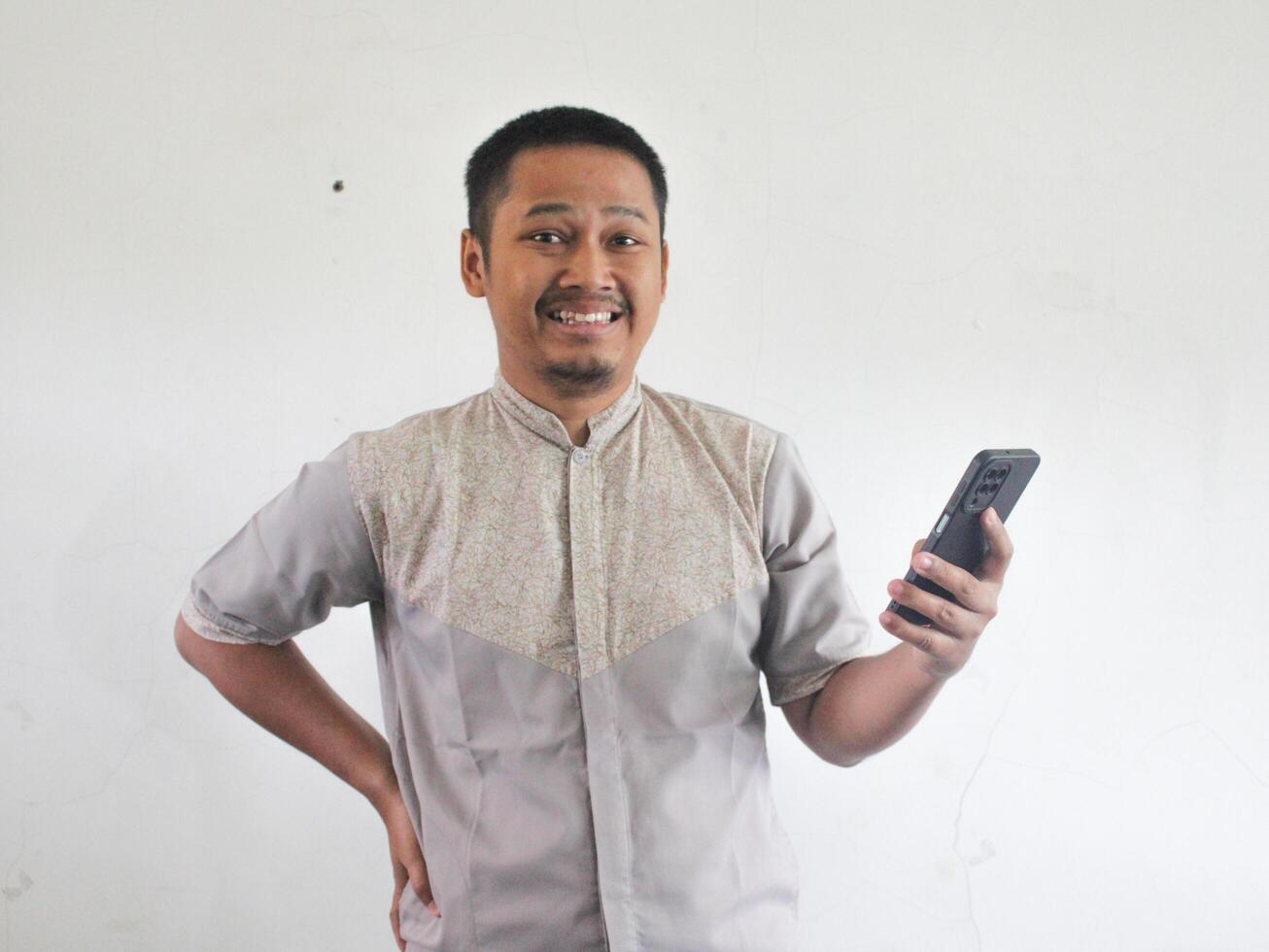 Adult Asian man smiling while using mobile phone photo