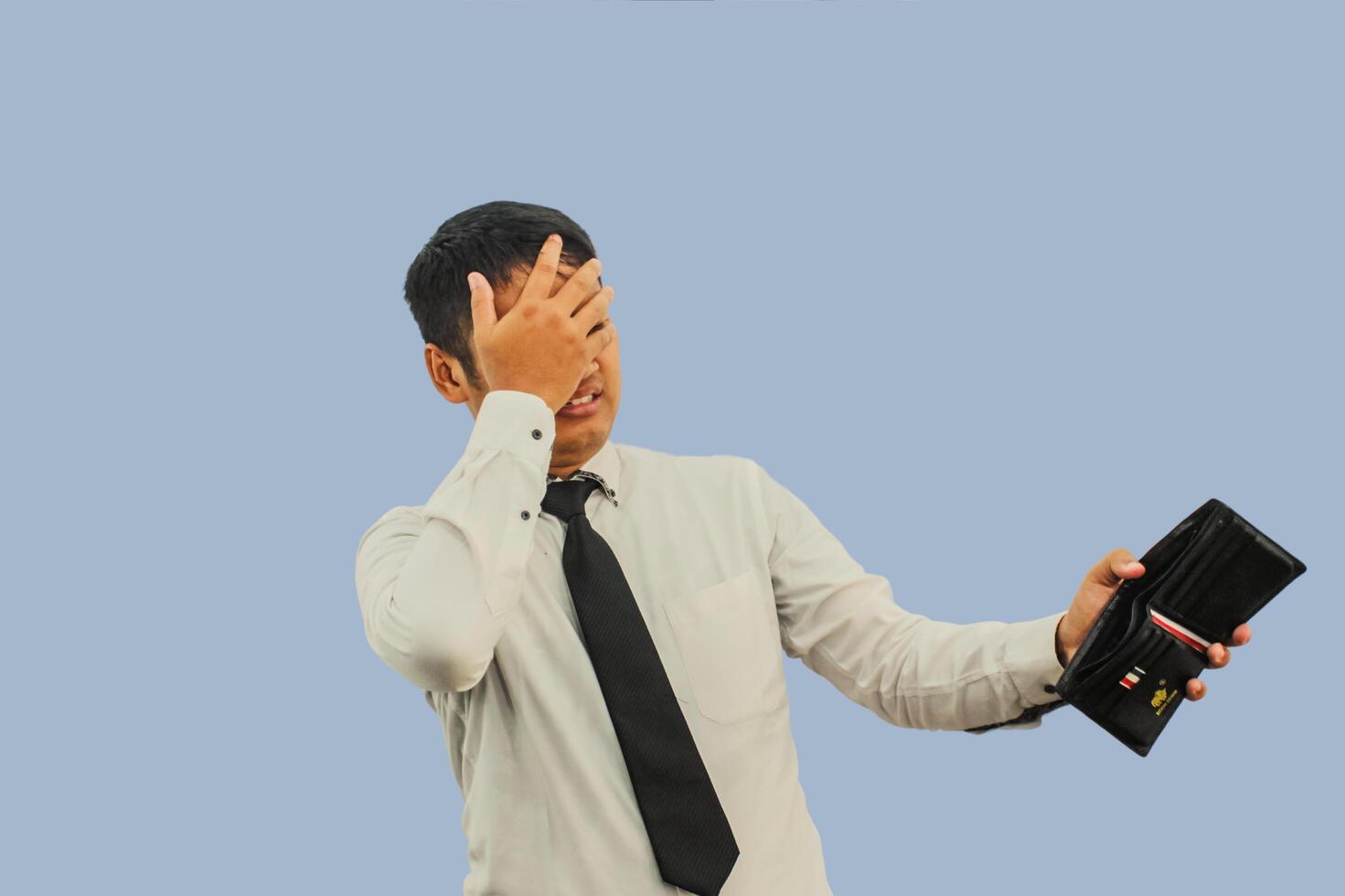 Adult Asian man showing shocked expression when looking to his empty wallet photo