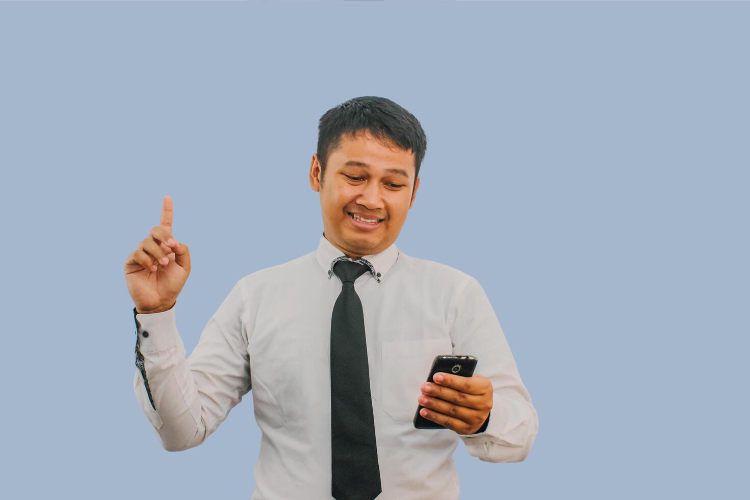 Adult man showing happy expression with finger pointing up when holding mobile phone photo
