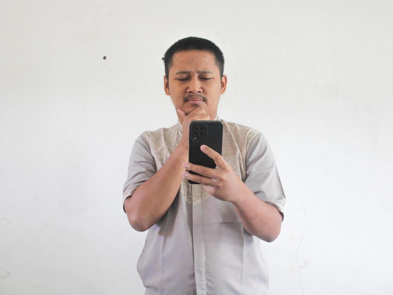 asiático hombre participación su móvil teléfono con grave expresión foto