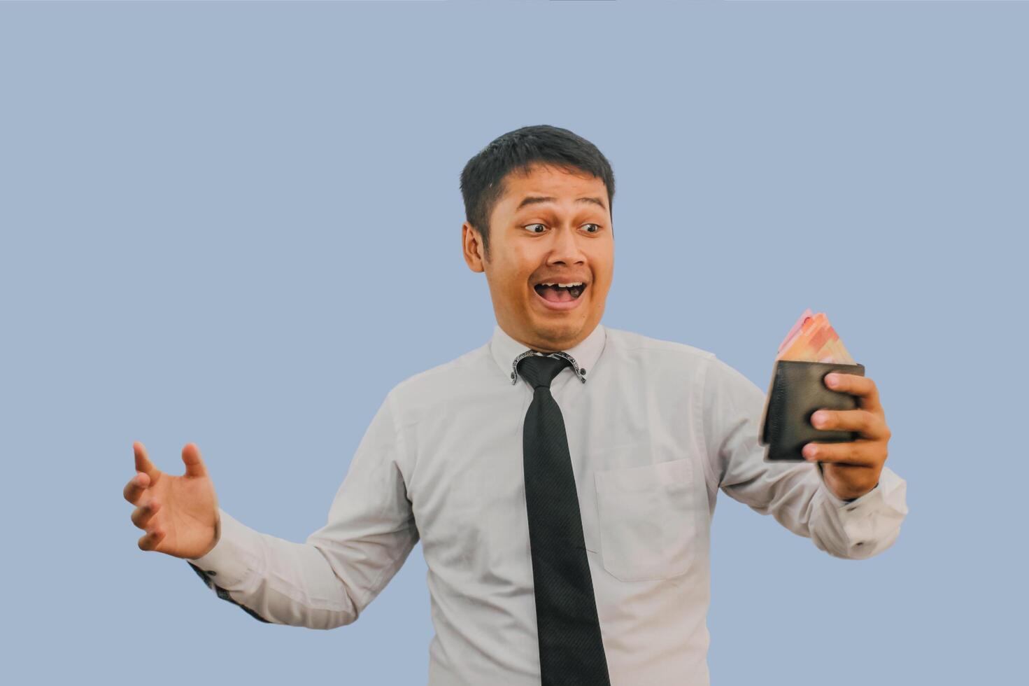 Adult Asian man showing amazed expression while holding his wallet full of money photo