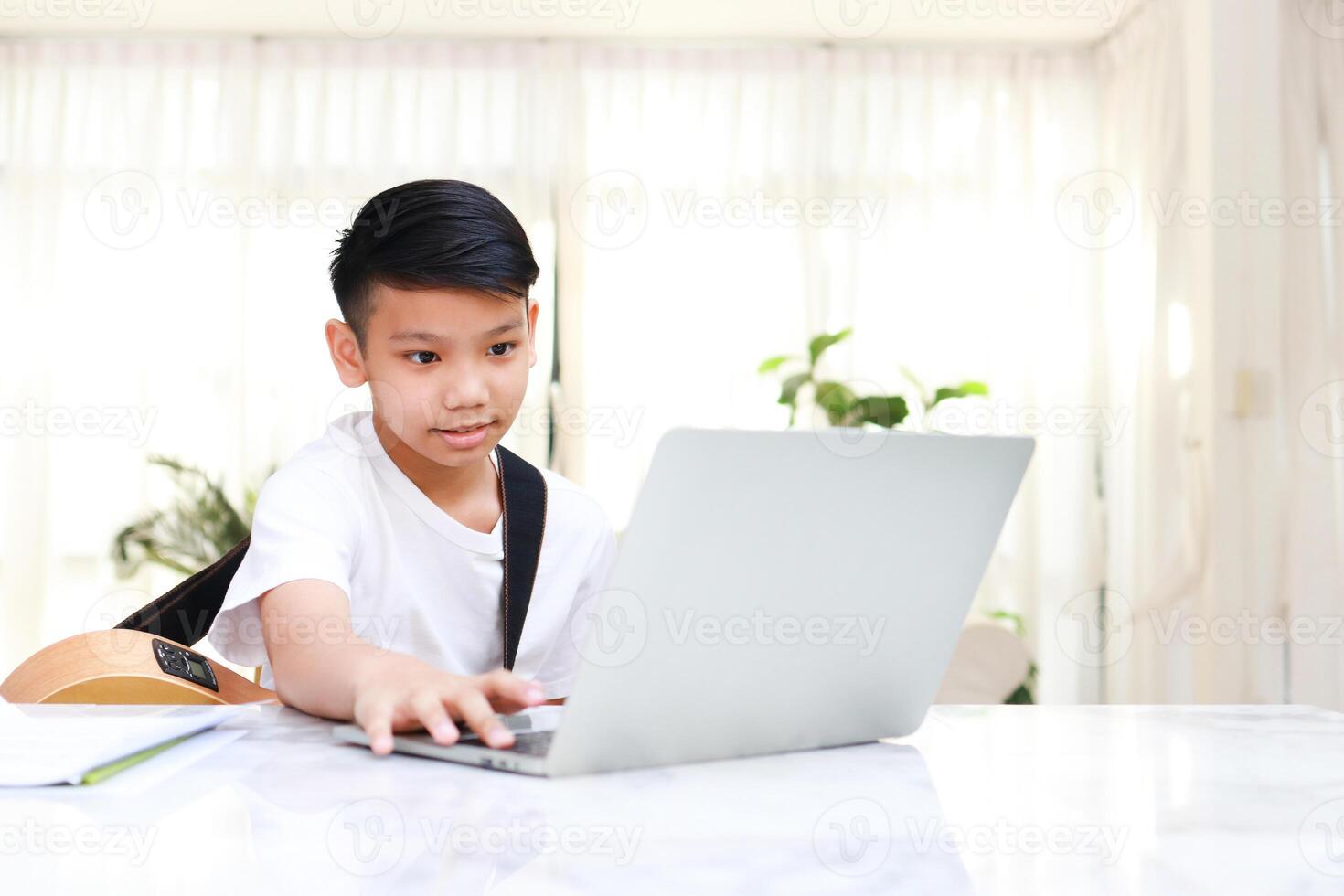 Asian boy learns music online at home through laptop. Concept of online education through the Internet. modern learning photo