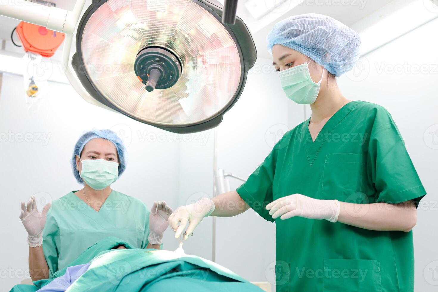 Professional team of Asian surgeons Perform surgery on a patient lying on a bed in a hospital operating room. Medical concepts. emergency surgery photo