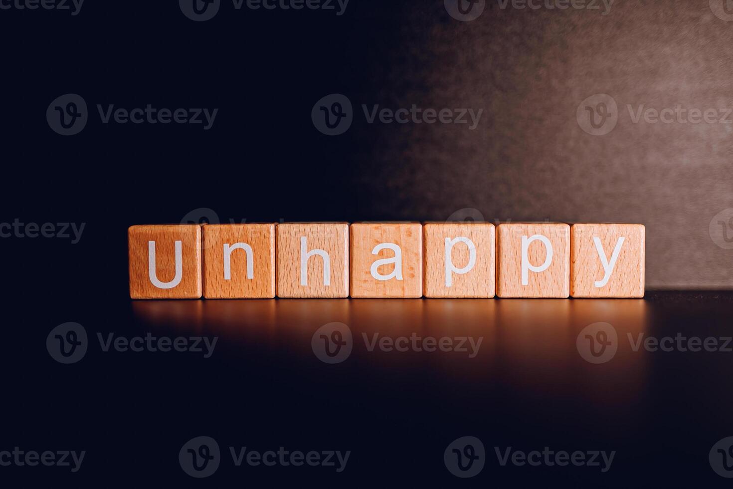 Wooden blocks form the text Unhappy against a black background. photo