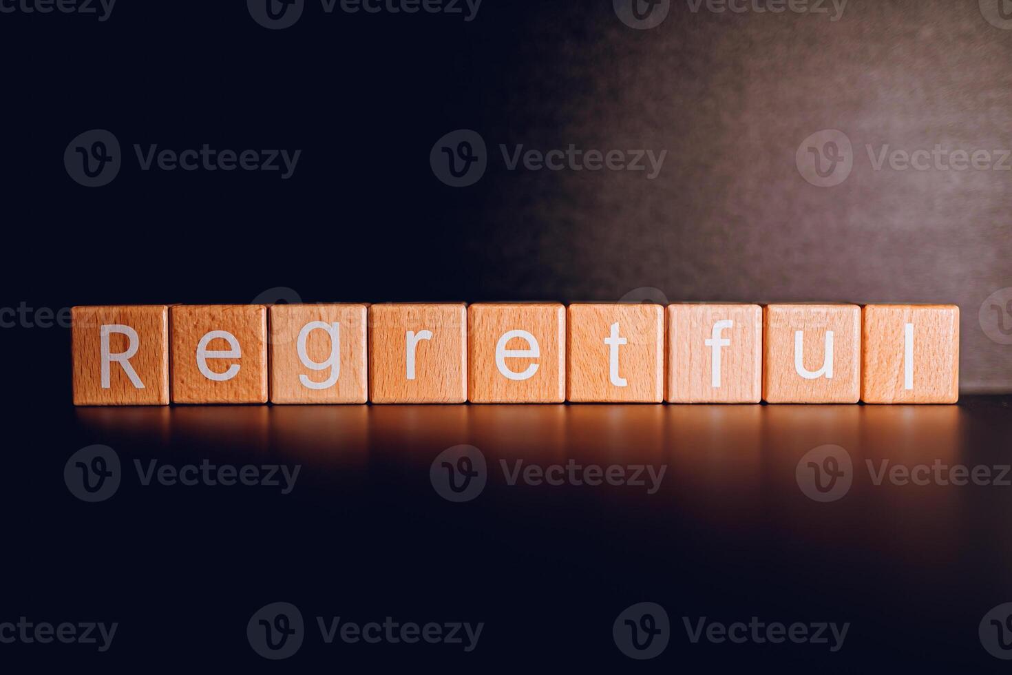 Wooden blocks form the text Regretful against a black background. photo