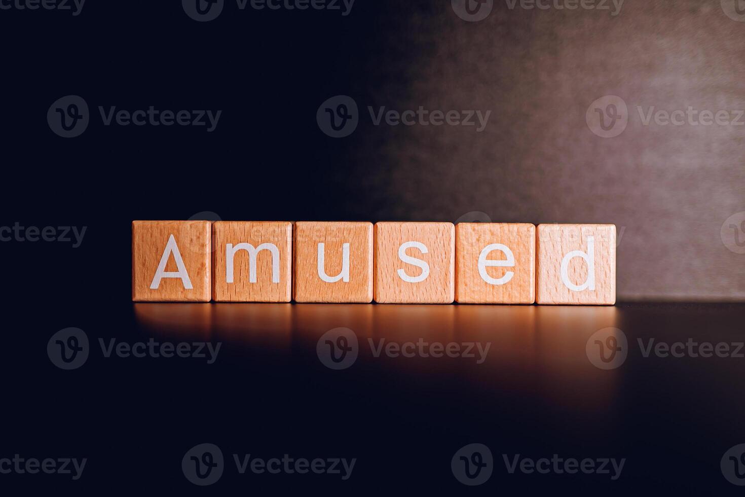 Wooden blocks form the text Amused against a black background. photo