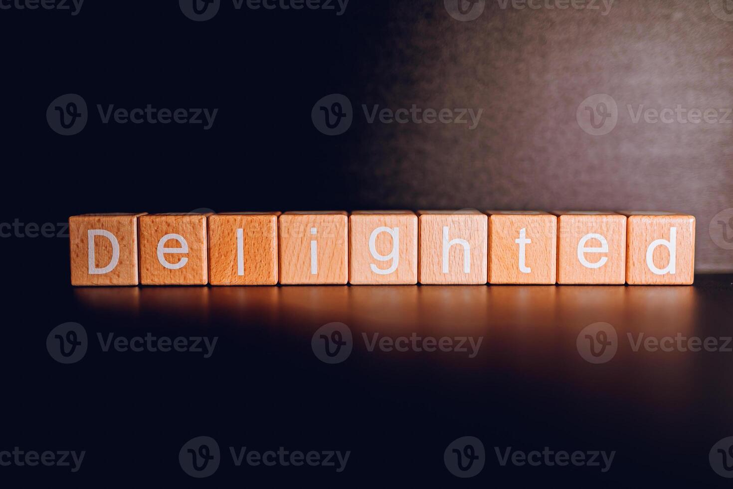 Wooden blocks form the text Delighted against a black background. photo