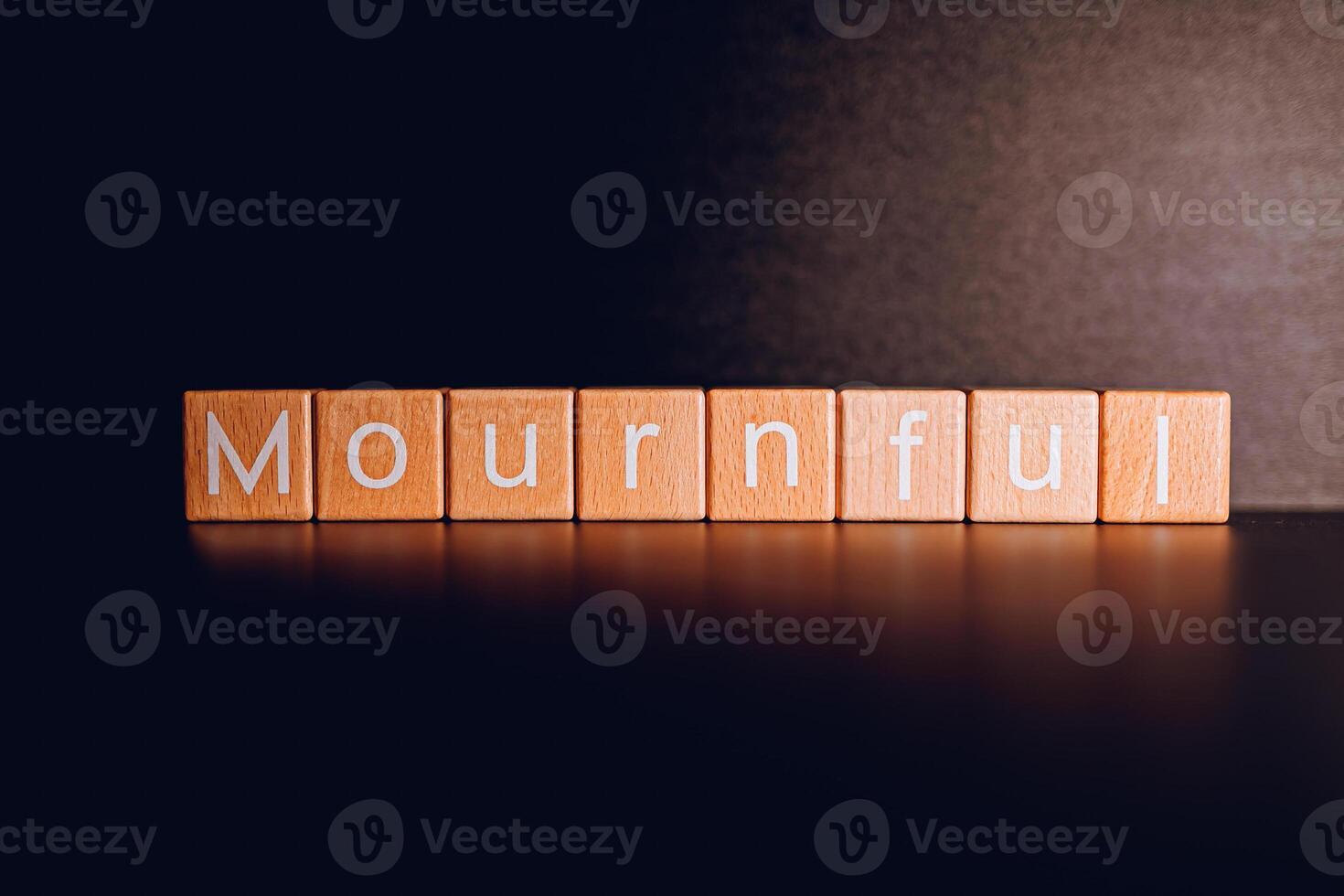 Wooden blocks form the text Mournful against a black background. photo