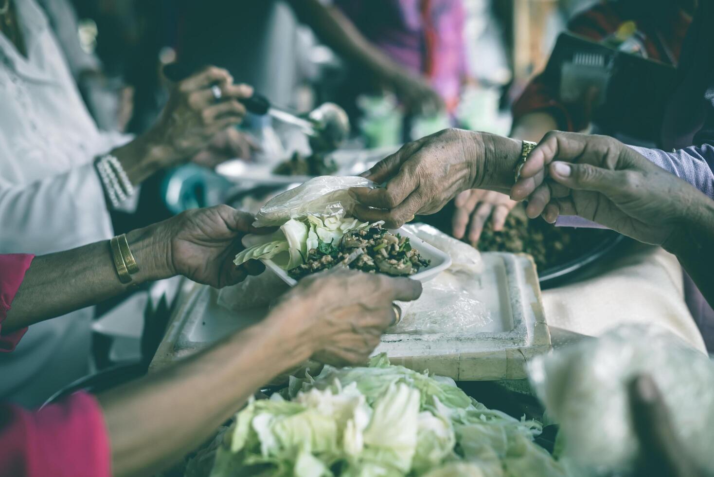 Hands of poor people asking for food from volunteers helping concept of food donation photo