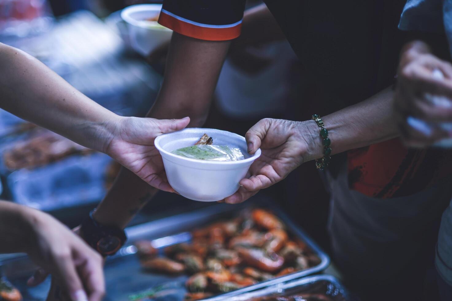 Hands of poor people asking for food from volunteers helping concept of food donation photo