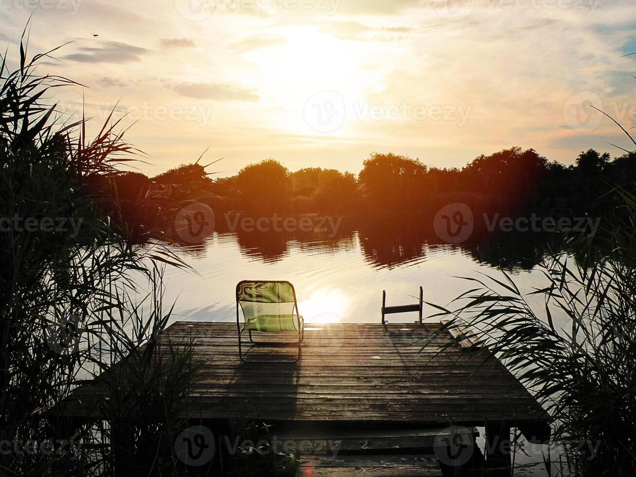 hermosa puesta de sol ver de el lago muelle con cubierta silla a verano o otoño foto