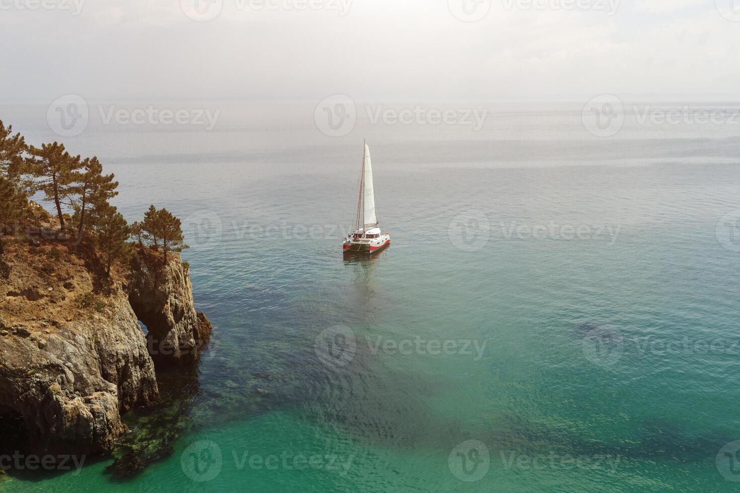 Panoramic view of Pacific Ocean blue transparent water, a white sport modern luxury yacht sail boat floating and a green shore with forest, hills. Holiday by the water and sail race. photo