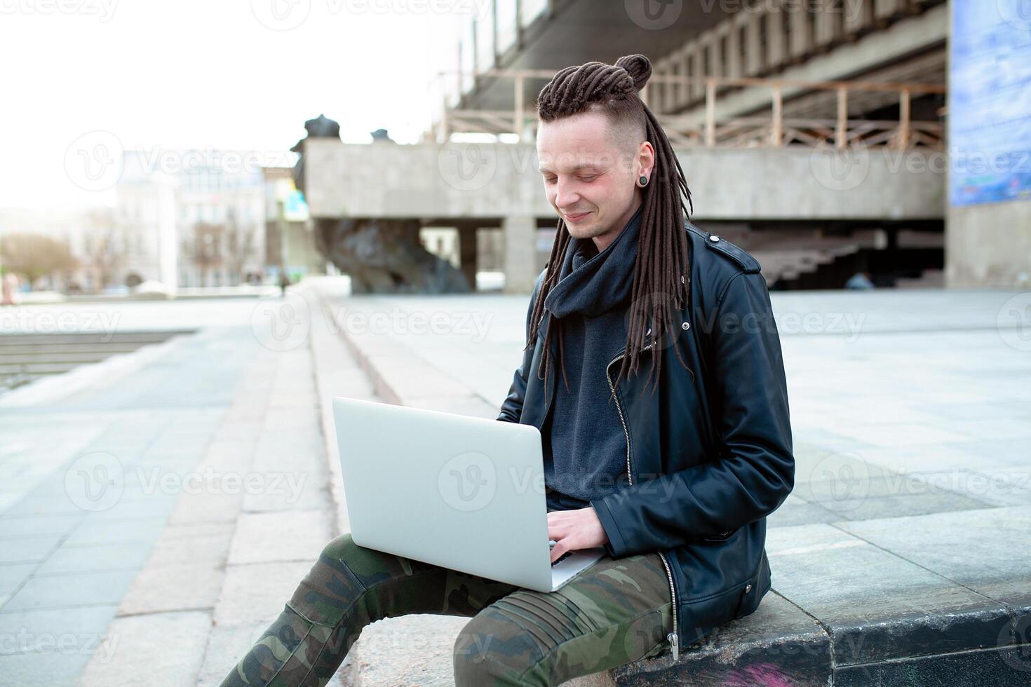 Young man sitting on the stairs using laptop photo