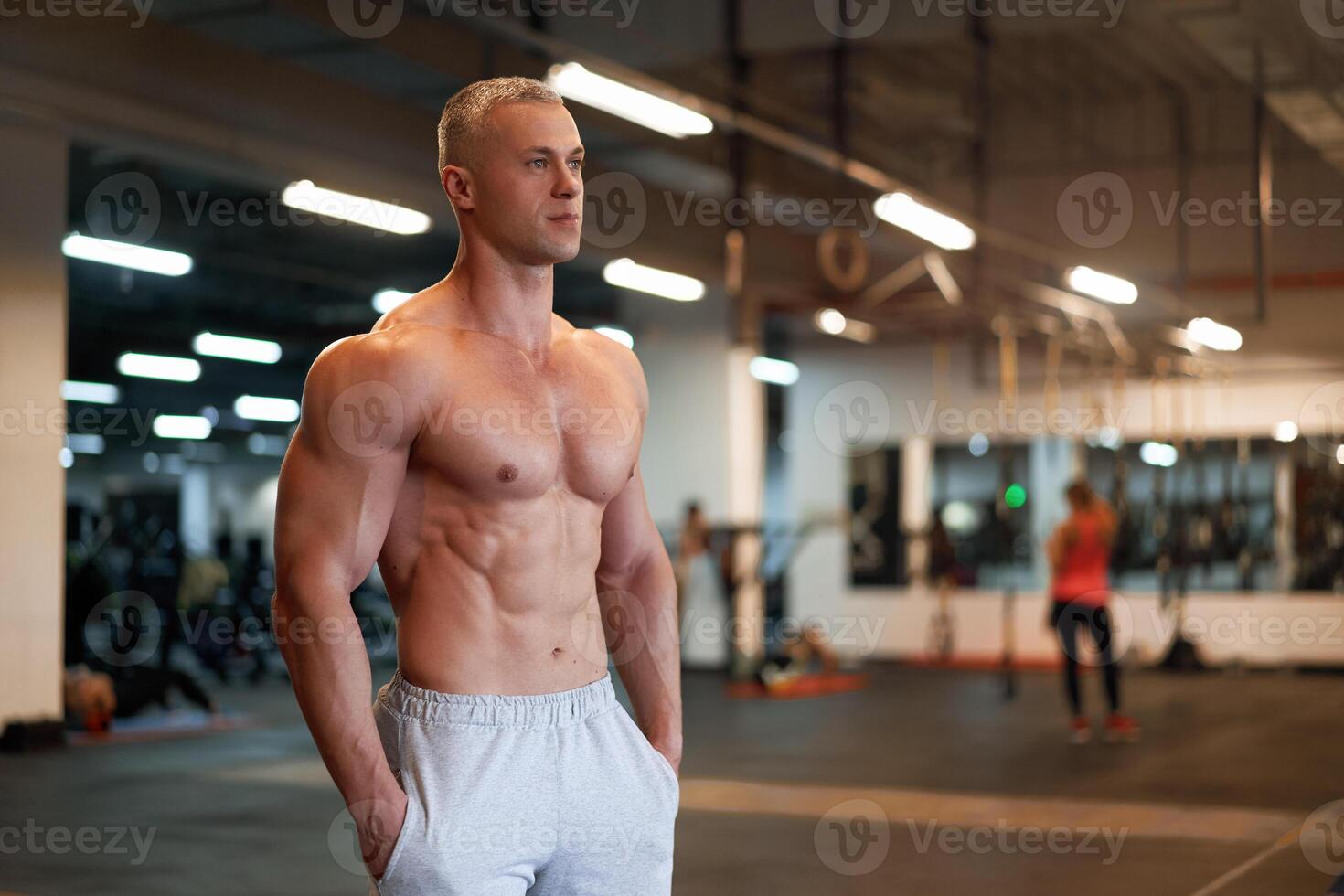 Muscular athletic bodybuilder fitness model standing gym photo