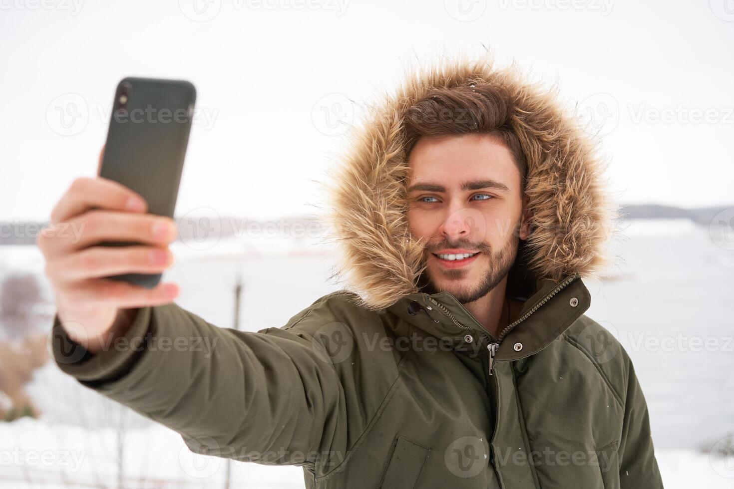 Attractive bearded man standing outdoors in winter season forest. photo