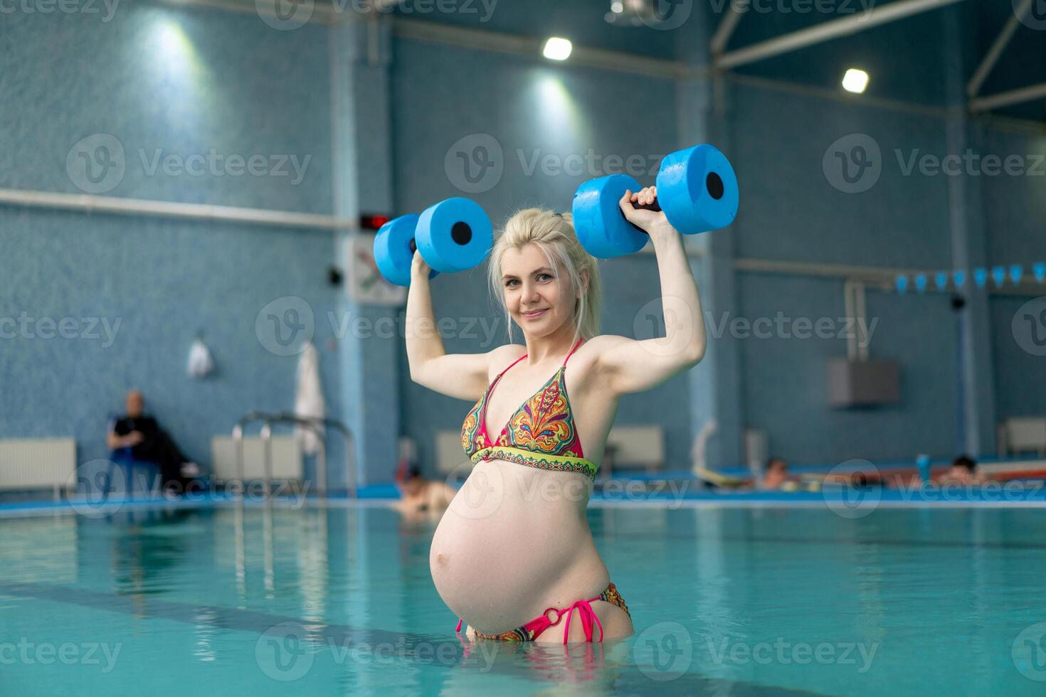 embarazada mujer en pie en agua con pesas adentro nadar piscina foto