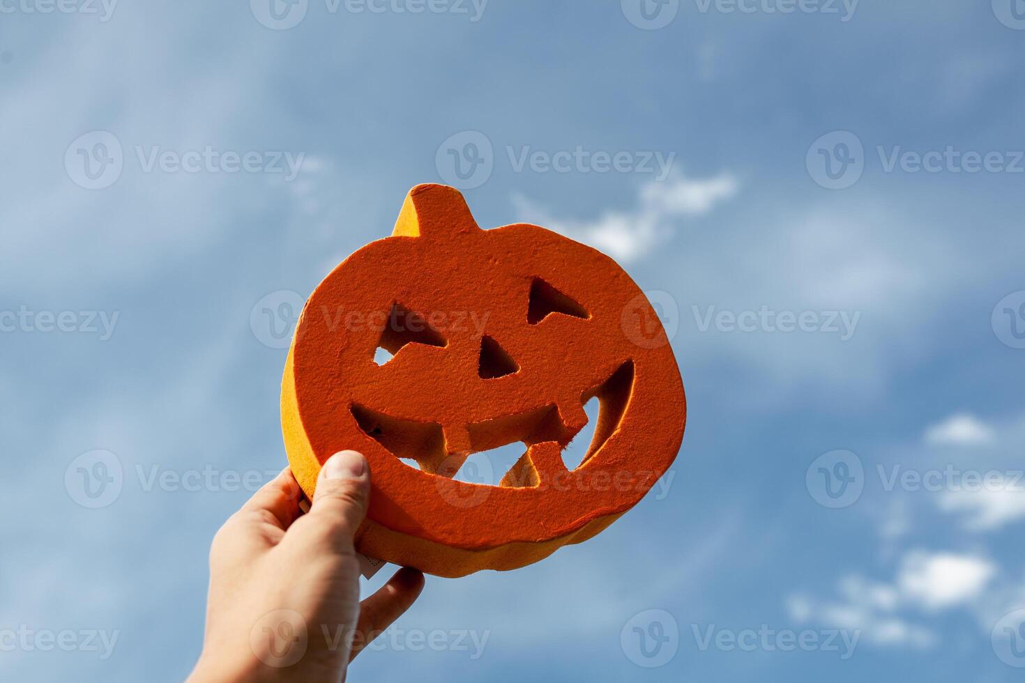 Halloween carved pumpkin in the man hand on the cloud sky background photo